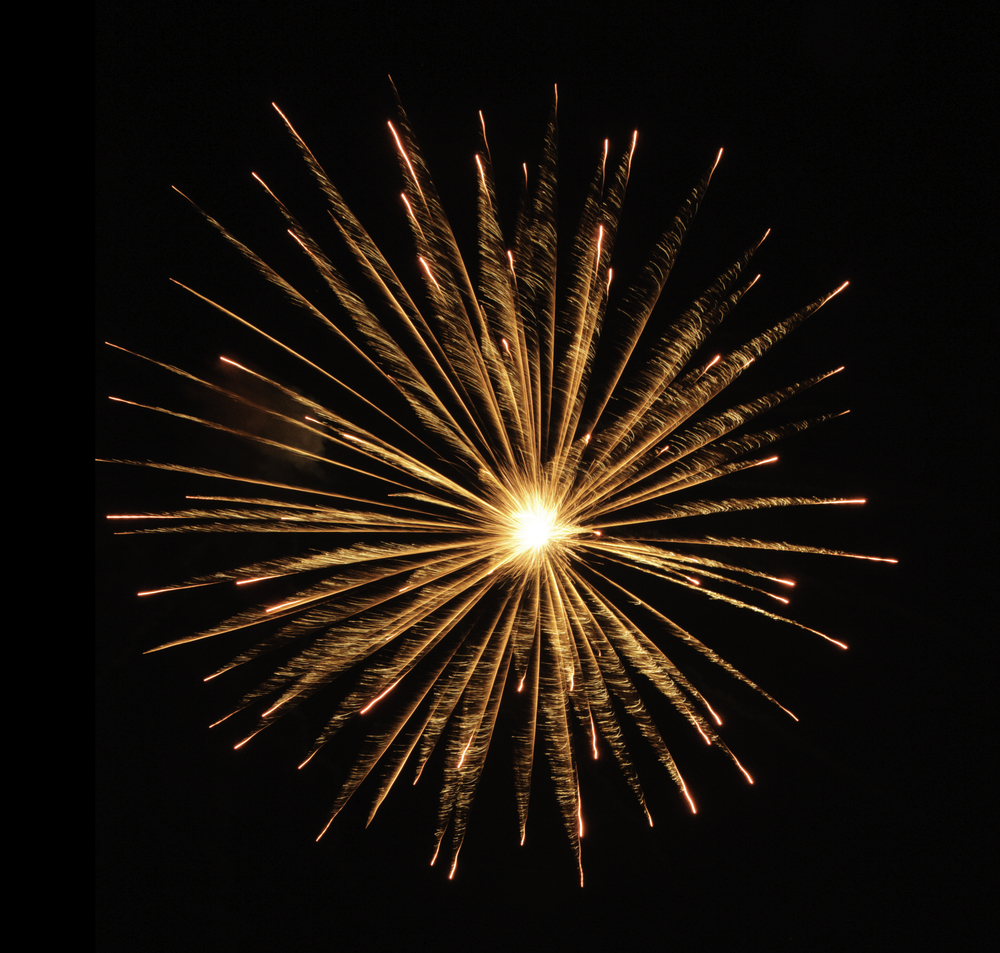 Round burst of orange fireworks with feathery motion blur and white-hot core of explosion