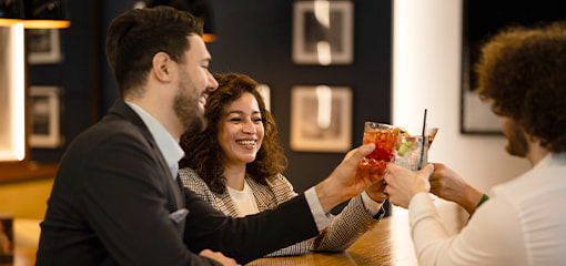 Three people clinking cocktail glasses